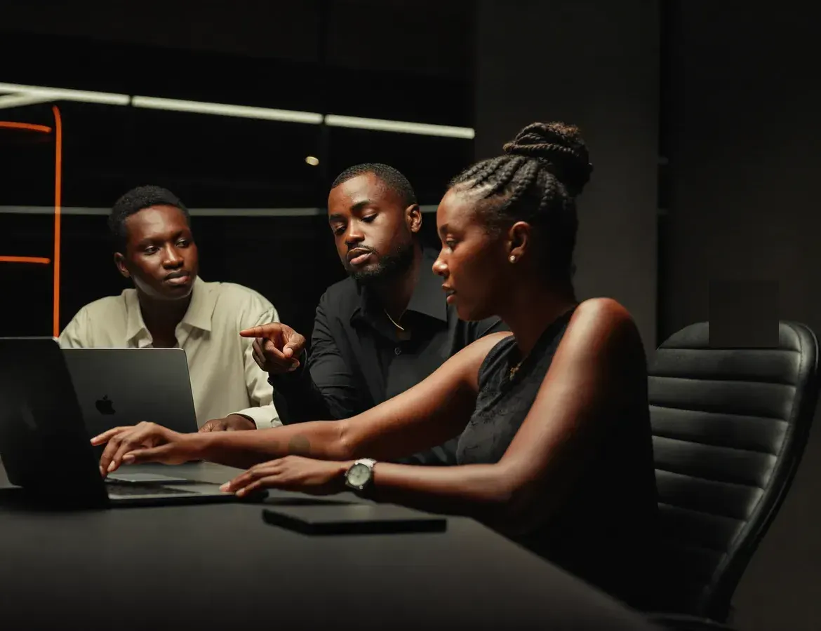 The StricherTech Solution team collaborating around a laptop in the studio.